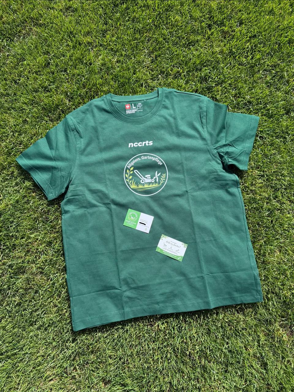 Grünes T-Shirt mit nccrts-Schriftzug und Logo von Allgaiers Gartenpflege, daneben Visitenkarten